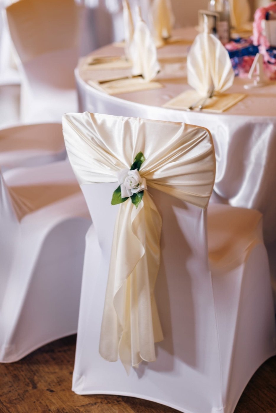 Stuhlhusse mit cremefarbener Satin-Schleife und weißer Rose