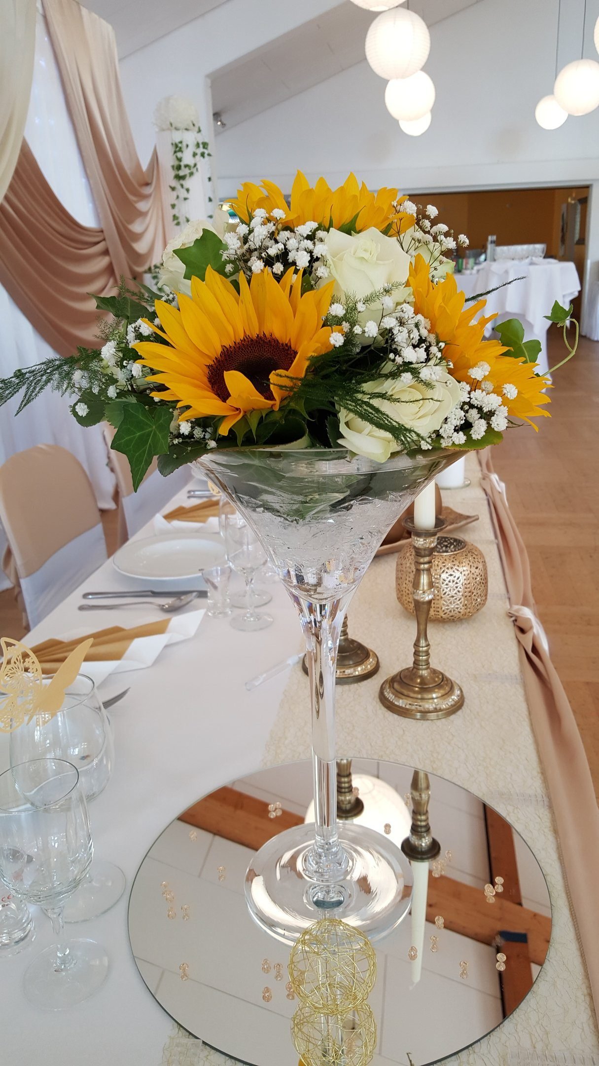 Blumendekoration in hoher Martini-Vase auf der Hochzeitstafel