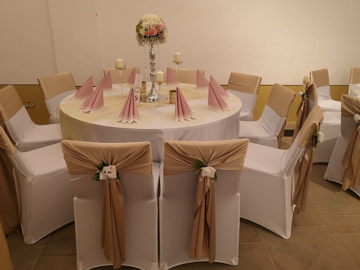 Gemietete Stuhlhussen mit Satin-Schleifen in Champagner und weißen Rosen an einer runden Festtafel